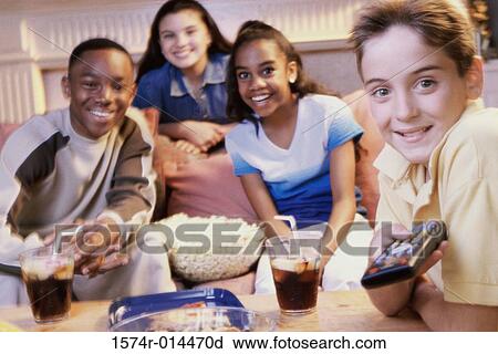 Stock Image - Two teenage girls and two teenage boys watching television. Fotosearch
