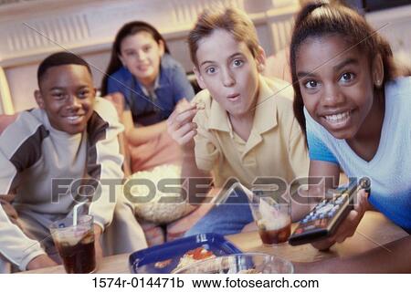 Stock Image - Two teenage girls and two teenage boys watching television. Fotosearch