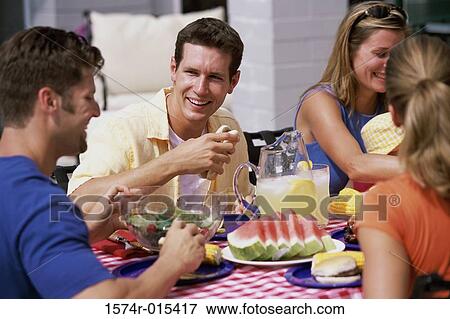 Two young couples sitting around a picnic table View Large Photo Image Stock Photo - Two young couples sitting around a picnic table. Fotosearch
