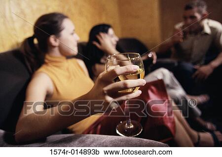 Stock Image - Two young women and a young man sitting in a bar. Fotosearch