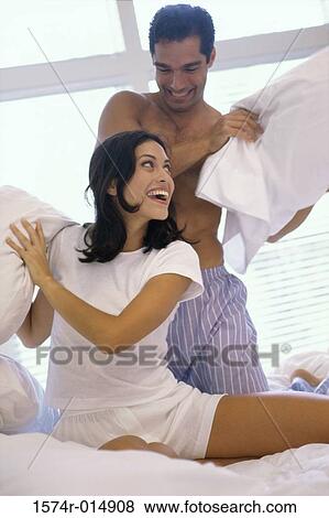 Young couple having a pillow fight in bed View Large Photo Image Stock Photo - Young couple having a pillow fight in bed. Fotosearch