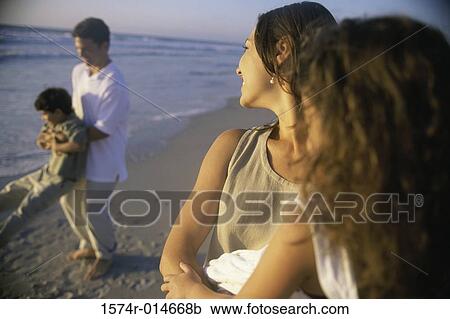 Stock Image - Young couple on the beach with their son and daughter. Fotosearch