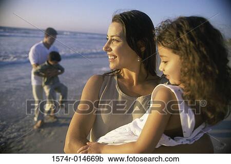 Stock Image - Young couple on the beach with their son and daughter. Fotosearch