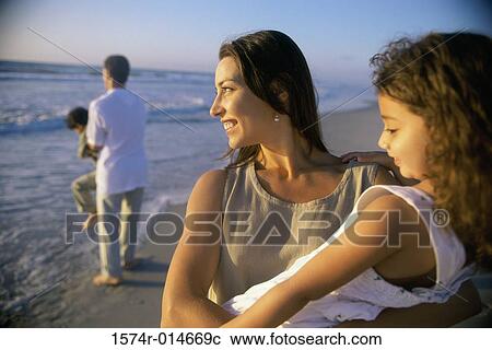 Stock Image - Young couple on the beach with their son and daughter. Fotosearch