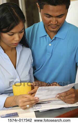 Young couple reading a bill View Large Photo Image Stock Image - Young couple reading a bill. Fotosearch