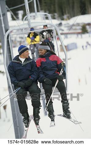 Young couple sitting on a ski lift View Large Photo Image Stock Image - Young couple sitting on a ski lift. Fotosearch