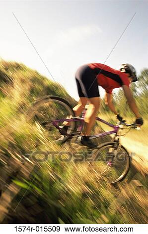 Young man cycling down a hill View Large Photo Image Stock Photo - Young man cycling down a hill. Fotosearch