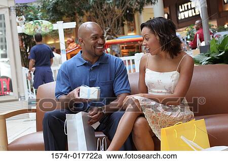 Stock Image - Young man giving a gift to a young woman. Fotosearch