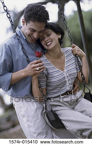 Young man giving a rose to a young woman sitting on a swing View Large Photo Image Stock Image - Young man giving a rose to a young woman sitting on a swing. Fotosearch
