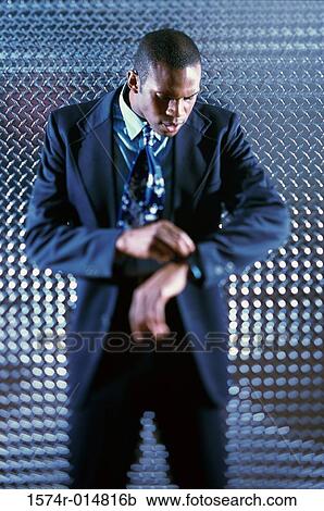 Young man looking at his wristwatch View Large Photo Image Stock Image - Young man looking at his wristwatch. Fotosearch