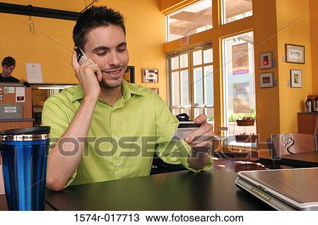 Young man talking on a mobile phone holding a credit card View Large Photo Image Stock Image - Young man talking on a mobile phone holding a credit card. Fotosearch