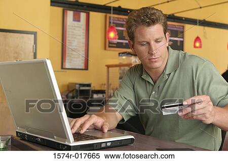 Young man using a laptop holding a credit card View Large Photo Image Stock Photography - Young man using a laptop holding a credit card. Fotosearch