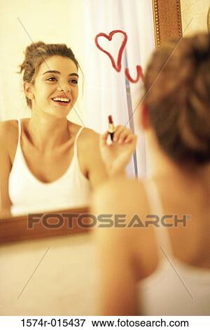 Young woman drawing a heart on a mirror with red lipstick View Large Photo Image Stock Photo - Young woman drawing a heart on a mirror with red lipstick. Fotosearch