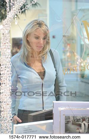 Stock Image - Young woman looking in a store window. Fotosearch