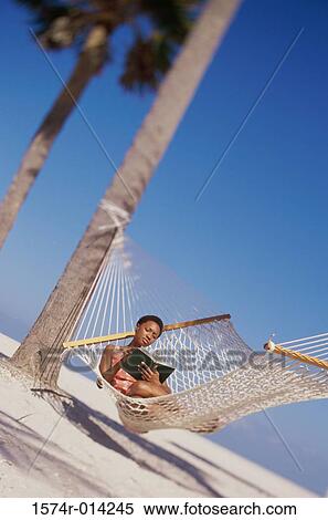 Young woman lying down in a hammock and reading a book View Large Photo Image Stock Photography - Young woman lying down in a hammock and reading a book. Fotosearch