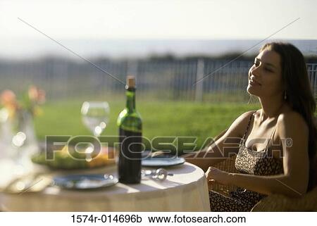Stock Image - Young woman sitting in a chair on a lawn. Fotosearch