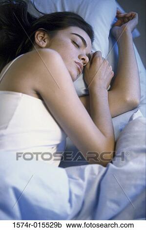 Stock Image - Young woman sleeping on a bed. Fotosearch