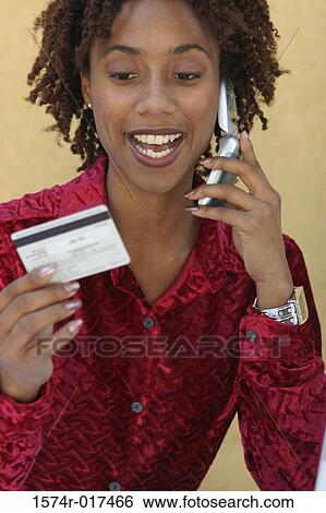 Young woman talking on a mobile phone holding a credit card View Large Photo Image Stock Photograph - Young woman talking on a mobile phone holding a credit card. Fotosearch