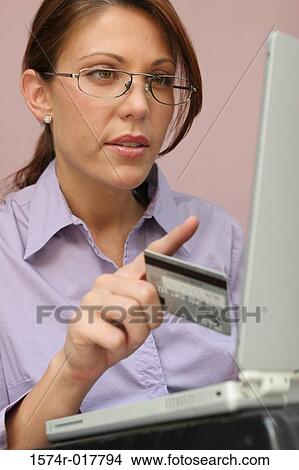 Young woman using a laptop holding a credit card View Large Photo Image Picture - Young woman using a laptop holding a credit card. Fotosearch
