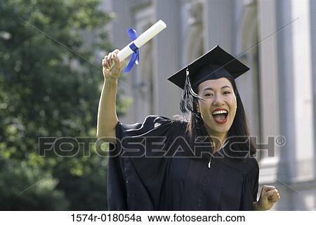 Young woman wearing a graduation gown and showing her diploma View Large Photo Image Stock Image - Young woman wearing a graduation gown and showing her diploma. Fotosearch