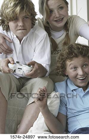 Close-up of a boy playing a video game with his friends View Large Photo Image Stock Photo - Close-up of a boy playing a video game with his friends. Fotosearch