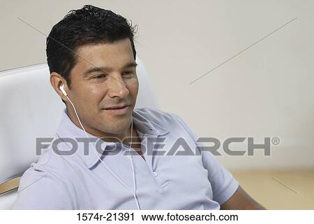 Close-up of a businessman wearing headphones and listening to music View Large Photo Image Stock Image - Close-up of a businessman wearing headphones and listening to music. Fotosearch