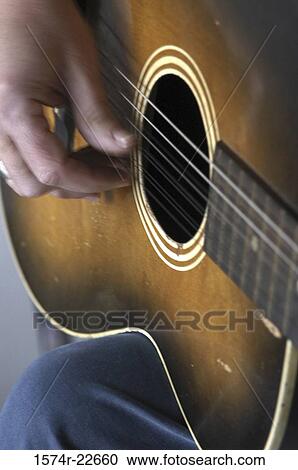 Close-up of a man plucking strings of a guitar View Large Photo Image Stock Image - Close-up of a man plucking strings of a guitar. Fotosearch