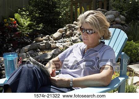 Close-up of a mature woman sitting in an adirondack chair and reading a document View Large Photo Image Stock Image - Close-up of a mature woman sitting in an adirondack chair and reading a document. Fotosearch