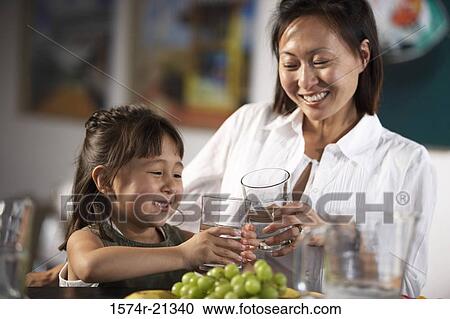 Stock Image - Close-up of a mid adult woman and her daughter toasting with glasses. Fotosearch