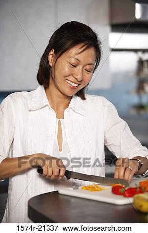 Close-up of a mid adult woman cutting a carrot on a cutting board View Large Photo Image Stock Photo - Close-up of a mid adult woman cutting a carrot on a cutting board. Fotosearch