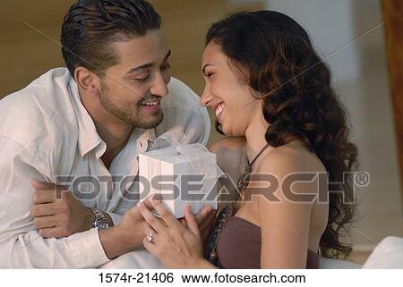 Stock Photograph - Close-up of a young man giving a gift to a young woman. Fotosearch
