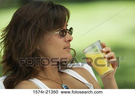 Close-up of a young woman drinking orange juice View Large Photo Image Stock Image - Close-up of a young woman drinking orange juice. Fotosearch