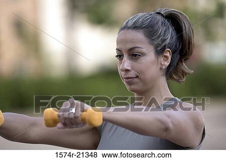 Stock Photo - Close-up of a young woman exercising with dumbbells. Fotosearch