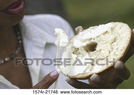 Close-up of a young woman holding a bagel View Large Photo Image Stock Photo - Close-up of a young woman holding a bagel. Fotosearch