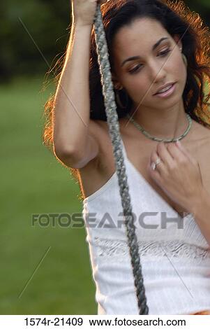 Close-up of a young woman sitting on a rope swing View Large Photo Image Stock Photo - Close-up of a young woman sitting on a rope swing. Fotosearch