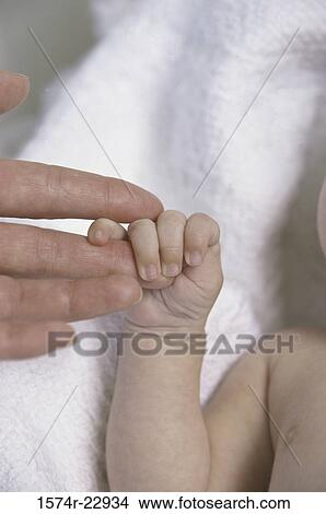 Picture - Close-up of an adult's hand holding a baby's hand. Fotosearch