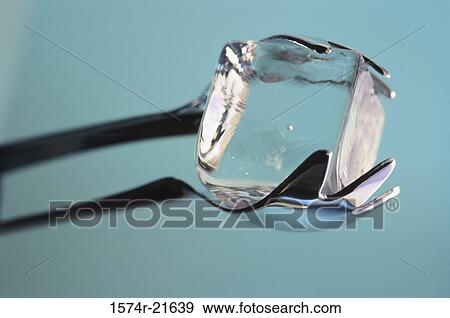 Stock Photo - Close-up of an ice cube held by tongs. Fotosearch