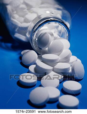 Stock Image - Close-up of tablets spilling out of an open bottle. Fotosearch