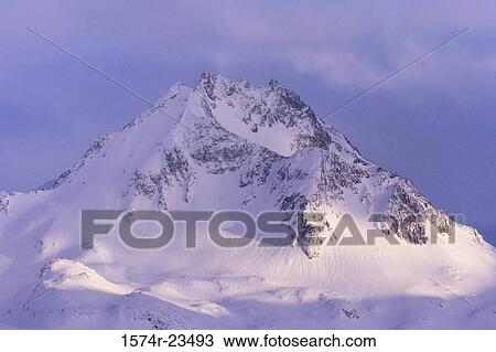 Stock Image - Clouds over a snow covered mountain, Kenai Peninsula, Alaska, USA. Fotosearch