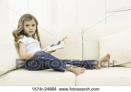 Girl holding a magazine on a couch View Large Photo Image Picture - Girl holding a magazine on a couch. Fotosearch
