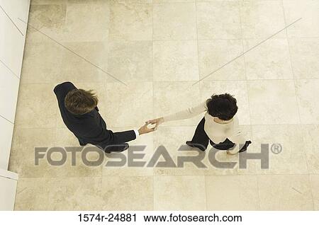 Stock Image - High angle view of a businessman shaking hands with a businesswoman. Fotosearch