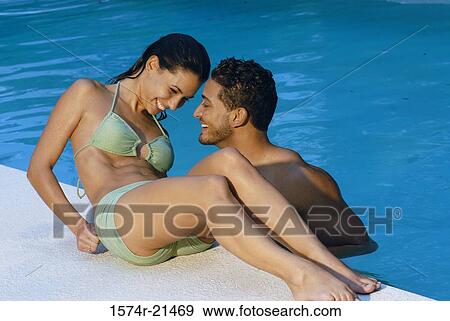 High angle view of a young man in a swimming pool with a young woman reclining at poolside beside him View Large Photo Image Stock Photo - High angle view of a young man in a swimming pool with a young woman reclining at poolside beside him. Fotosearch