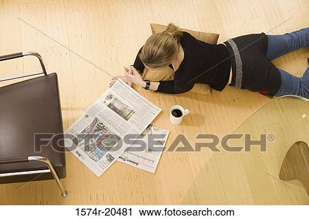 Stock Image - High angle view of a young woman reading a newspaper. Fotosearch