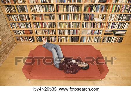 High angle view of a young woman wearing headphones and listening to music on a couch View Large Photo Image Stock Image - High angle view of a young woman wearing headphones and listening to music on a couch. Fotosearch