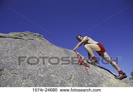 Low angle view of a young man climbing up a rock face View Large Photo Image Stock Image - Low angle view of a young man climbing up a rock face. Fotosearch