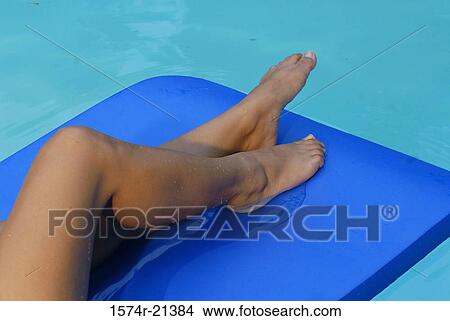 Low section view of a woman lying on a pool raft in a swimming pool View Large Photo Image Picture - Low section view of a woman lying on a pool raft in a swimming pool. Fotosearch