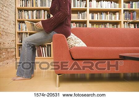 Stock Image - Low section view of a young woman holding a book. Fotosearch