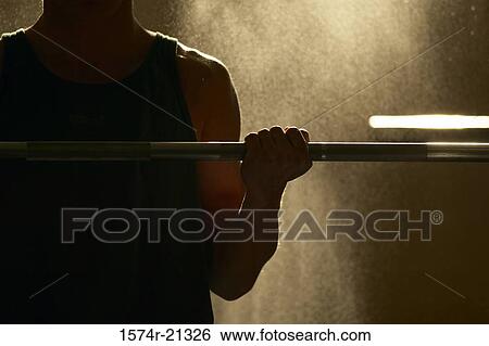 Stock Photograph - Mid section view of a man exercising with a barbell. Fotosearch