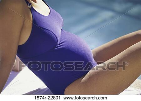 Mid section view of a pregnant woman in a swimsuit sitting beside a swimming pool View Large Photo Image Stock Image - Mid section view of a pregnant woman in a swimsuit sitting beside a swimming pool. Fotosearch