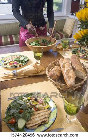 Stock Photograph - Mid section view of a woman mixing salad in a bowl. Fotosearch